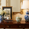 Decorative table setting with floral arrangement, books, and ceramic vases on a wooden surface.